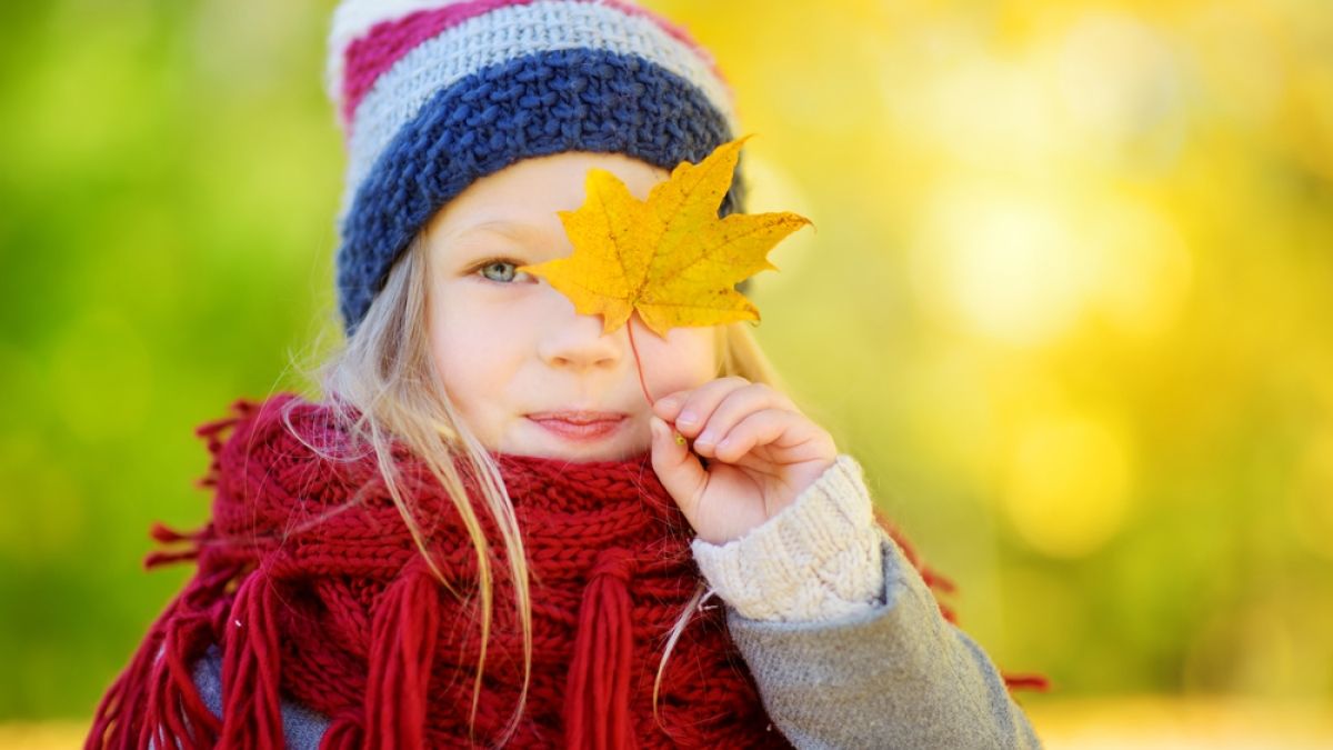 young girl hold yellow leaf over eye